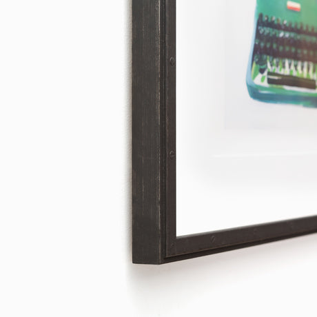 Green typewriter art in riveted black frame at angle