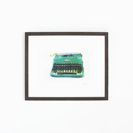 Green typewriter art in riveted black frame on white wall