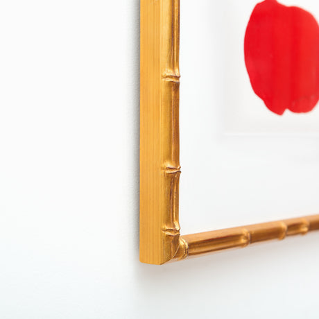 Red abstract art in gold bamboo frame at angle